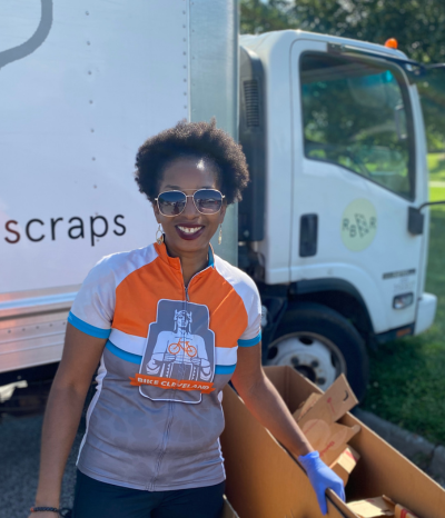 Deltrece standing on side of Rust Belt Riders box truck smiling next to a large cardboard box